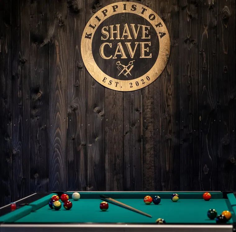 Útskorið Shave Cave merki og billjardborð inni á klippistofunni í Reykjavík